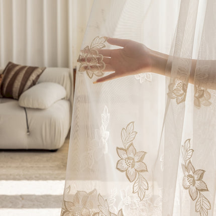 a woman's hand on a sheer curtain in a living room