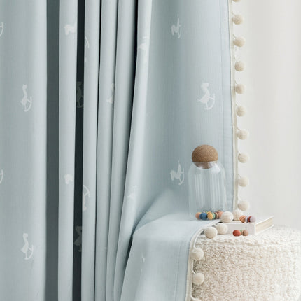a white bed sitting next to a window covered in curtains