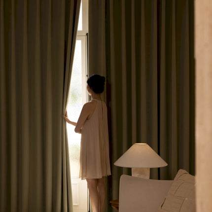 a woman standing in front of a window next to a lamp