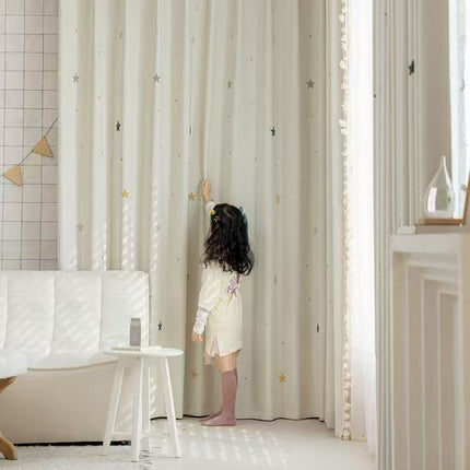 a little girl standing in front of a curtain