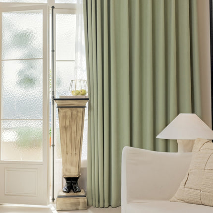a living room with a white couch and green curtains