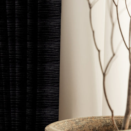 a plant in a vase next to a curtain