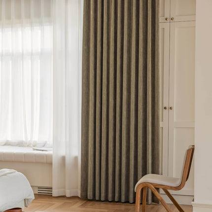 a bedroom with a bed, chair and curtains
