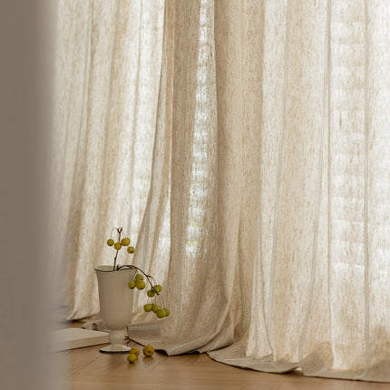 a vase with a plant in it sitting in front of a curtain
