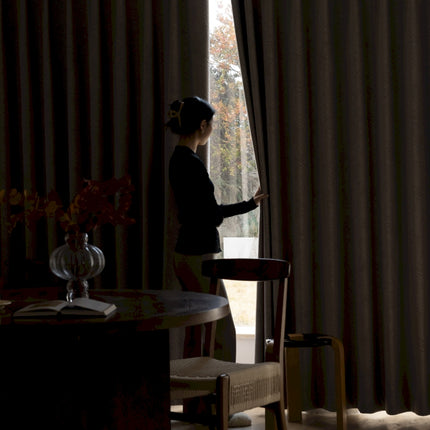 a woman standing in front of a window next to a table