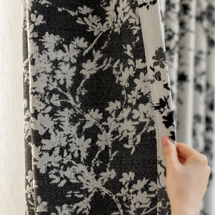 a person is holding up a black and white curtain