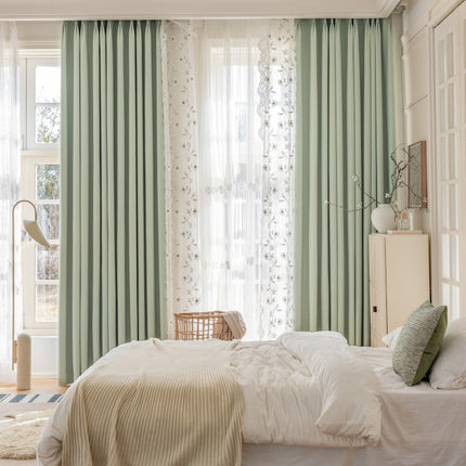 a bedroom with green curtains and a white bed