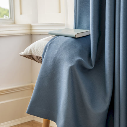 a bed with a blue blanket and a book on top of it