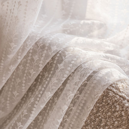 a close up of a bed with white lace on it