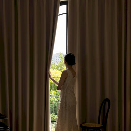 a woman in a wedding dress looking out a window