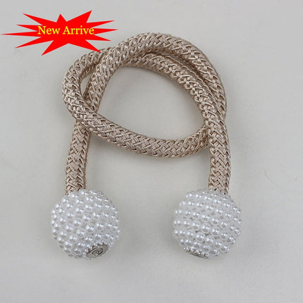 Une paire de perles beige et blanche sur une corde, utilisée comme attache pour rideaux décoratifs.
